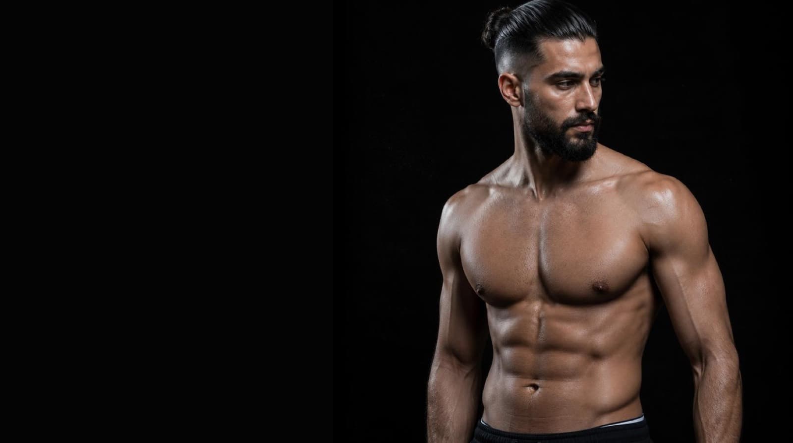 Lean athletic man in black training apparel in a dark gym